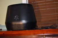 Front view of black Lomi composter on shelf, power cord visible