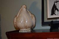 Side view of cream speckled ceramic penguin figurine on furniture
