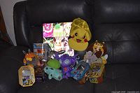 Full lot on couch showing plush, tins, hat, figure pack, lenticular print