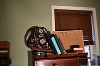 Backpacks, bulletin board, binders stacked on cabinet