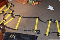 Ladder partially extended on floor showing yellow rungs and black straps