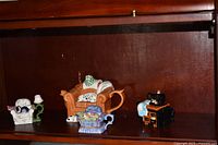 Shelf view showing four small novelty teapots