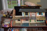 Wide shot of tin litho dollhouse with board games and other toys nearby