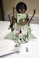 Front view of clock showing dial, whimsical mechanical parts, and paperwork