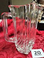 Frontal view of clear crystal pitcher showing fluted sides and handle
