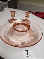 Top view of pink depression glass bowl with two candlesticks in background