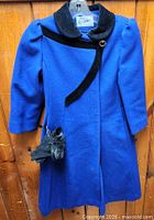 Full view of blue wool coat on hanger with gloves attached