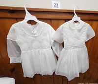 Front view of both white dresses on hangers