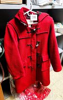 Front view of red wool duffle coat on hanger showing overall design