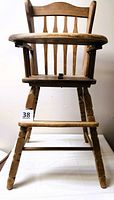 Full front view of wooden highchair showing tray, seat, legs, and footrest
