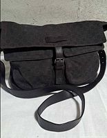 Front view of Gucci GG denim messenger bag with strap and buckle flap visible