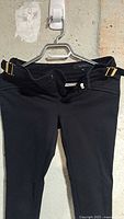 Front view of black Gucci knit pants showing waistband, gold buckles, fly