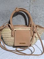 Front view of Jacquemus Soli rattan basket bag showing leather handles, strap and logo patch