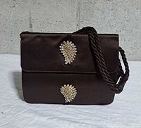 Front view showing satin exterior, jeweled appliques, cord strap