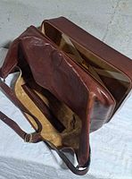 Bag open showing lined main compartment, interior zip pocket, adjustable strap