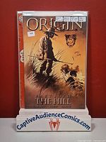 Front view of bagged Origin #1 showing cover art, price sticker, and display stand