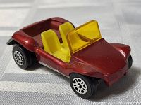 Front three-quarter view showing metallic red body, yellow seats and windshield, wheels