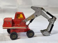 Side view of red Matchbox Lesney excavator showing boom, bucket, cab and wheels