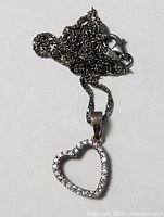 Necklace coiled showing lobster clasp and heart pendant with clear stones