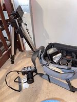 Full lot showing tripod, camera bag with contents, Canon SLR with lens