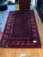 Full view of red and black rectangular rug on wood floor