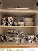 Cabinet shelves showing plates, bowls, cups, teapot, platter