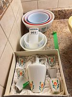 Stacked milk-glass bowls and boxed decanter set on countertop