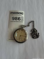 Front view of Omega pocket watch with chain and MaxSold tag 986C