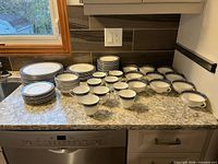 All pieces arranged on countertop: plates, bowls, cups.
