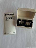 Cufflinks in presentation box beside lot card