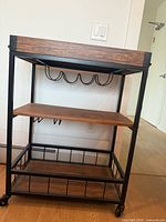 Full view of bar cart showing frame, shelves, wine glass rack, wheels