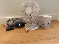 Desk fan, Roku player with cables, boxed Chromecast displayed on floor