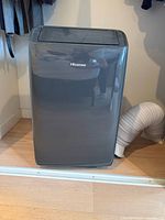 Front view of Hisense portable air conditioner showing brand badge and attached exhaust hose