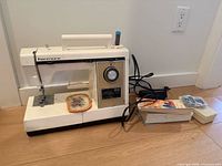 Kenmore sewing machine with foot pedal, power cord, thread spool and stack of accessories