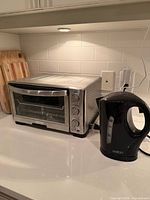 Toaster oven and Salton kettle on countertop under cabinet light