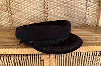 Front side view of black wool Greek Fisherman cap on wicker background