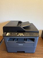 Front and left side view of Brother MFC-L2710DW printer on table