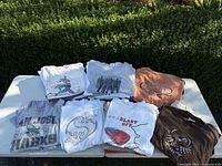 Overview of eight folded graphic T-shirts on table