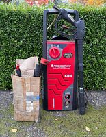 Front view of Powerwasher H2010 unit standing upright with attachments in paper bag