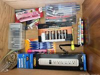Drawer containing power strip, batteries, pens, pencils, clips, rubber bands