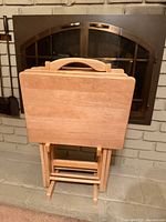 Front view of stacked wooden TV trays on stand