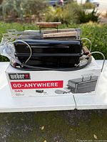 Grill on top of original box with two wooden-handled utensils