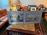 Both framed prints on coffee table showing scale and framing