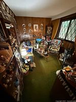 Wide view of room showing sofa, coffee table, wall decor plates, side table, lamps, collectibles