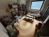 Overall view of room showing sofa, coffee table, rug, bookshelf, chair, floor lamp, red vase (excluded)