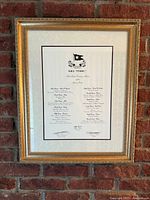 Full view of framed Titanic menu reproduction on brick wall