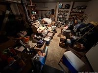 Wide view of garage showing boxes, bins, cooler, shelves of mixed items