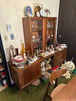 Full view of teak cabinet with glass uppers and assorted décor on and inside