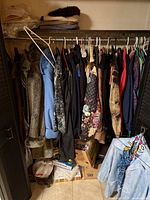 Closet rod with assorted vintage women’s clothing, fur coat, denim shirt, boxes below