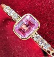 Ring showing bezel-set pink sapphire and shoulder diamonds